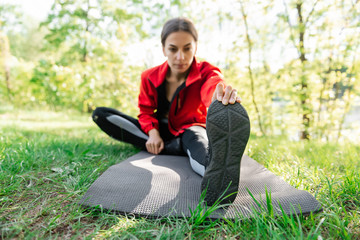 Obraz premium young girl is warming up stretching before training in the forest