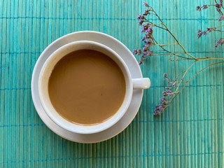 white cup of coffee and flowers on turquoise
