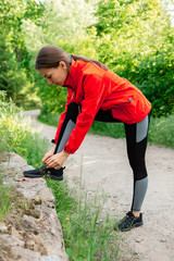 young girl tying shoelaces on sneakers before jogging in nature