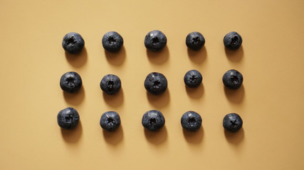 Blueberries are laid out in rows on a gold background - perfectionism concept