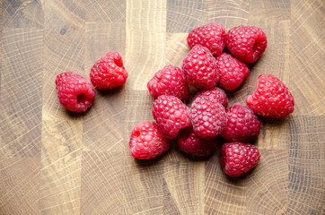 Close-up raspberries on wooden background with copy space. Sweet raspberries on wooden table. Close up, top view, selective focus. Harvest Concept. Fresh raspberries on a brown wooden surface.