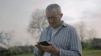 Close up farmer man with glasses use mobile phone in garden countryside rural producer telephone speaking cell discussion farm culture outdoors male portrait close up