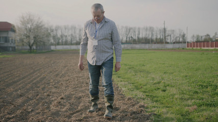 Portrait of a happy man farmer in nature checks the ground on field green meadow park adult agriculture garden male worker casual one person close up