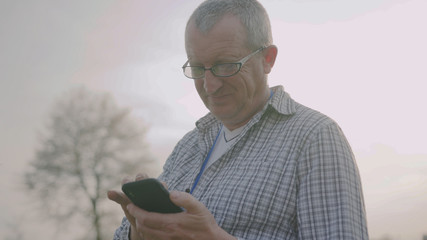 Close up farmer man with glasses use mobile phone in garden countryside rural producer telephone speaking cell discussion farm culture outdoors male portrait close up