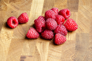 Close-up raspberries on wooden background with copy space. Sweet raspberries on wooden table. Close up, top view, selective focus. Harvest Concept. Fresh raspberries on a brown wooden surface.