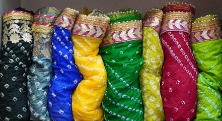 Traditional Rajasthan dress materials is neatly stacked for sale in a cloth merchant shop in India....