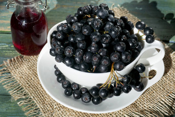 Fresh black chokeberry  (Aronia melanocarpa), juice in a bottle on a wooden background