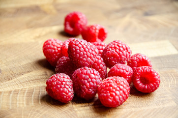 Close-up raspberries on wooden background with copy space. Sweet raspberries on wooden table. Close up, top view, selective focus. Harvest Concept. Fresh raspberries on a brown wooden surface.