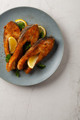 Fried carp in pieces, served on a gray plate. Marbled bright background.
