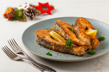Fried carp in pieces, served on a gray plate. Marbled bright background.