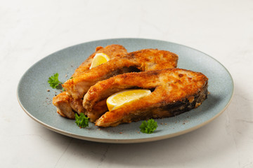 Fried carp in pieces, served on a gray plate. Marbled bright background.