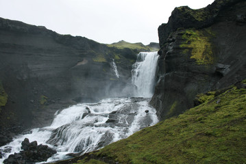 Waterfall in a scenic landscape with rocks and ice water coming from the glacier in Iceland