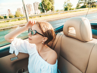 Portrait of young beautiful and smiling hipster girl in convertible car. Sexy carefree woman...