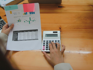 Fototapeta na wymiar Businesswoman or accountant working pointing graph discussion and analysis data charts and graphs and using a calculator.