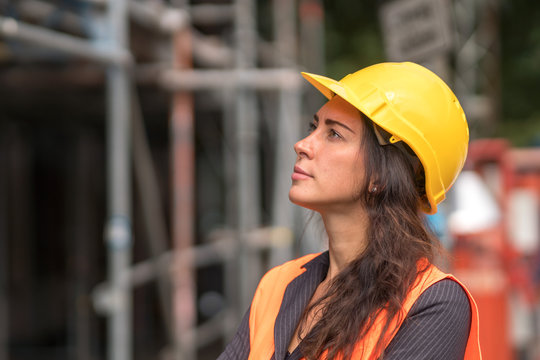 Profile Portrait Of An Attractive Female Factory Worker Wearing A Yellow Protective Helmet And Looking Aside