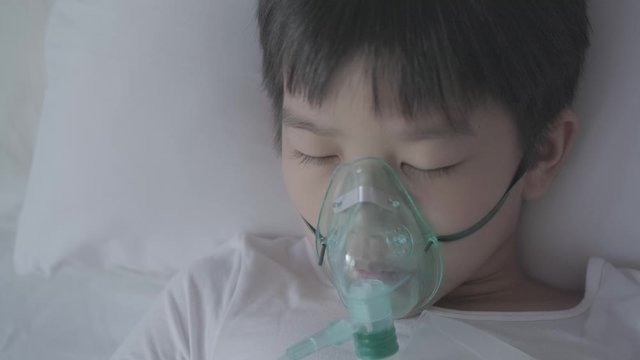 4k Top view Young asian boy with oxygen mask sleep on a bed looking outside of window with sad eye