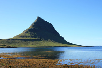 Massive volcanic green hill  next a river in Iceland