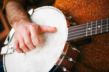 Close up of a Male Banjo player relaxing on the porch, practicing and picking away