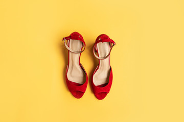 Top view of red womens stylish shoes on yellow background with copy space, flat lay