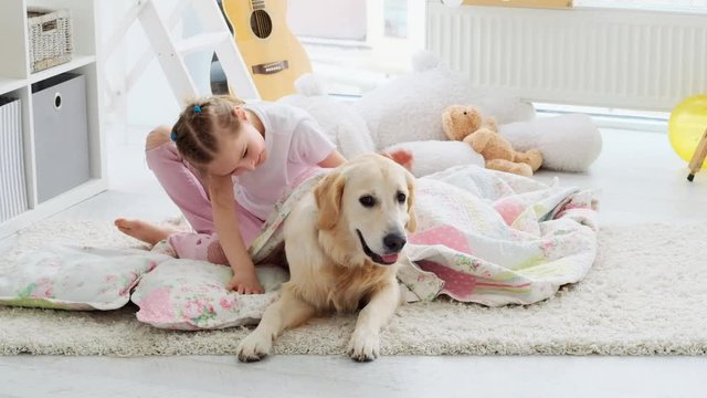 Happy little girl playing with cute dog in beautiful play room