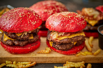 Set of four homemade giant double becon cheese burgers. Served with french fries on wooden board.