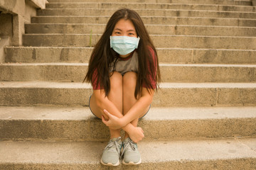 new normal urban portrait - young happy and beautiful Asian Chinese woman in face mask sitting...