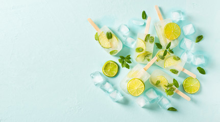 Popsicle ice cream flat lay with lime and mint on blue background with slice of lime and leaves mint