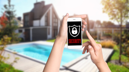 Alarm system. Woman using phone outdoors, closeup