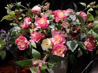 beautiful bouquet of pink and yellow roses in a white vase on wooden table black marble background, artificial flowers