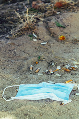Used medical masks and and cigarrettes on the floor. Face mask concept.