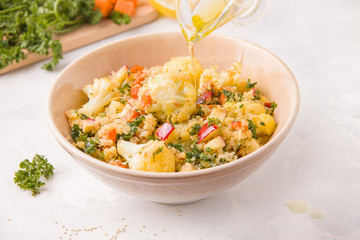 Salad with cauliflower, quinoa, apple and olive oil in a plate