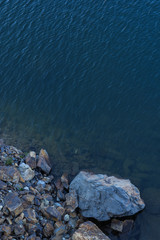 Stone rocks near water, on the background of lake, river, sea, ocean. Blue clear water. Artificial reservoirs