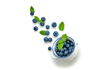 Blueberry flying in air, isolated on white. Fresh blueberry falling into bowl closeup, healthy diet concept. Ripe organic bilberry, mint leaf fly, creative minimal levitation concept.