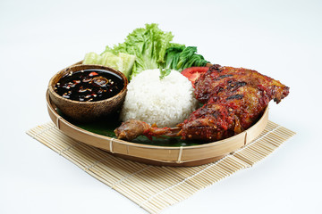 Grilled chicken legs with brown skin are laid out on a wooden sheet on a white background, plus...