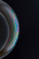 Current collection of brilliant backgrounds for your design. Cropped shot of a blurry blob against a soap bubble with iridescent stains on it's surface on the black backdrop. 
