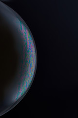 Current collection of brilliant backgrounds for your design. Close-up shot of a soap bubble with iridescent stains on the surface on the black backdrop. 