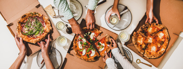 Pizza party for friends or family. Flat-lay of pizzas in boxes, lemon drinks and peoples hands...