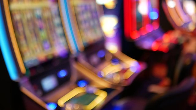 Defocused slot machines glow in casino on fabulous Las Vegas Strip, USA. Blurred gambling jackpot slots in hotel near Fremont street. Illuminated neon fruit machine for risk money playing and betting.