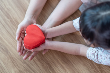 Mother and child daughter hands holding red heart gift boxes, Happy family concept