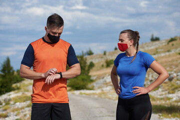 couple of running in nature wearing mask having a break