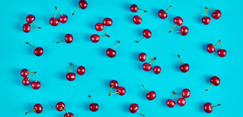 Red cherry colorful pattern on blue background. Fresh berry closeup, organic cherry wallpaper, top view. Juicy berries, mint creative concept, fashionable trendy flat lay