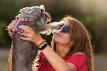 young girl in sunglasses, raised the dog up, smiling, braces on the teeth