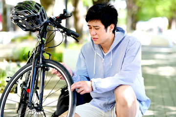 Obraz premium 自転車のトラブルに困る若い男性