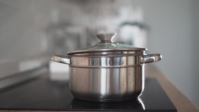 Kitchen video. close-up Boiling pan on the stove. White steam from hot water. Cooking process. Shot in 4k