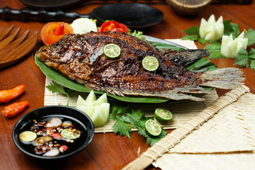 photos of food products, View from above Close up of grilled fish or grilled gouramy with chili sauce and vegetables on a textured wooden table. Usually used for menu list pictures or food pictures in