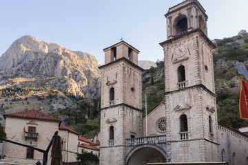 Fototapeta na wymiar Medieval church with towers in Kotor (Montenegro) in mountains. Architectural decorations of buildings- columns, tops, gypsum stucco molding.