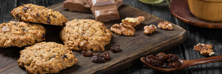 Oatmeal cookies. Oatmeal cookies on a wooden serving Board on a black wooden table. Banner