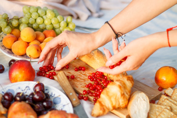 French picnic. picnic composition in nature. summer berries and fruits, baguette. hands hold berries.