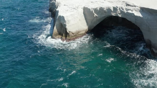 Aerial View of Sarakiniko Lunar Volcanic Beach with Waves crashing into rocks in Milos, Greece
