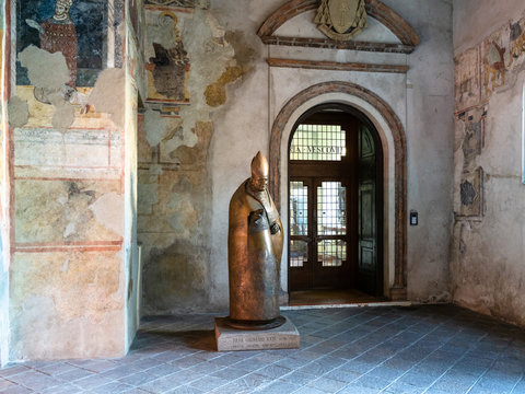 BERGAMO, ITALY - FEBRUARY 19, 2019: statue of Papa Giovanni XXIII in old aula Tempietto di Santa Croce and Basilica di Santa Maria Maggiore in Upper Town (Citta Alta) of Bergamo city, Lombardy